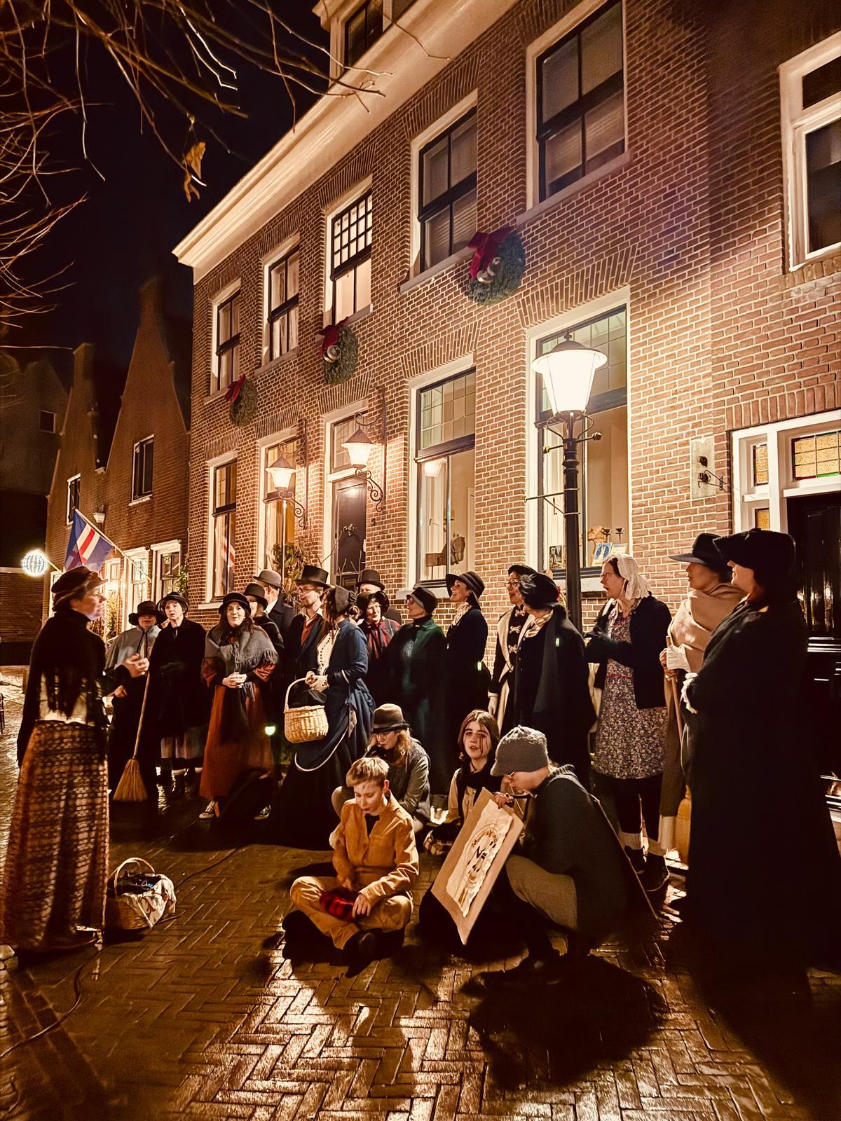 Bezoekers in historische kleding luisteren op straat naar een verteller